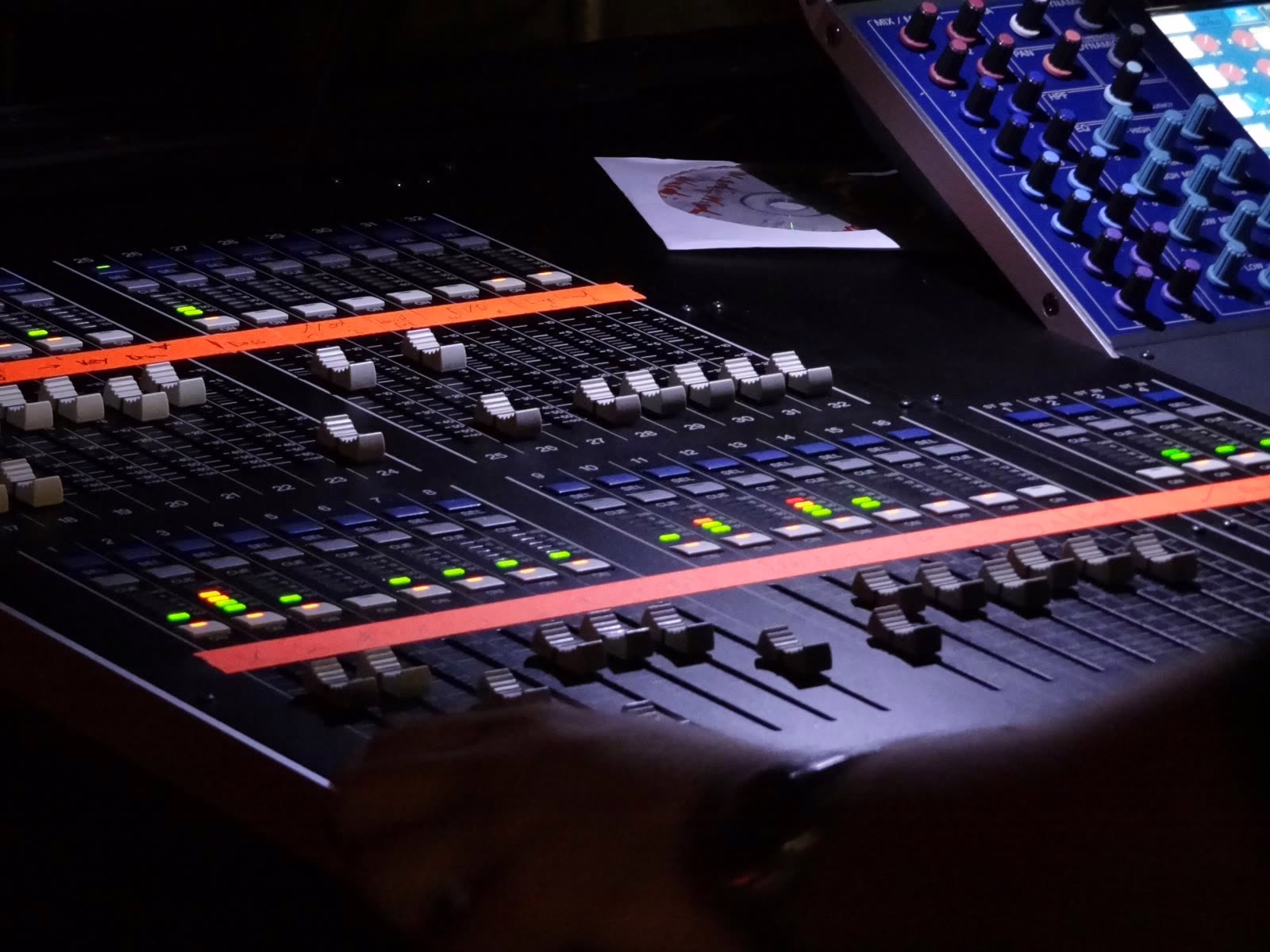 Digital live console with handwritten gaffer tape strips marking the fader layers