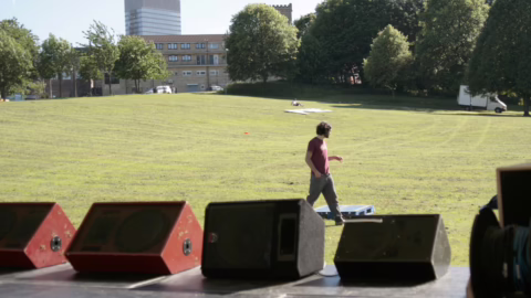 Quatre retours de scène de type wedge alignés au bord d'un plateau de concert en plein air