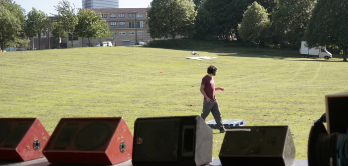 Quatre retours de scène de type wedge alignés au bord d'un plateau de concert en plein air
